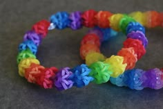 two rainbow bracelets are sitting on the floor together, one is made out of plastic beads