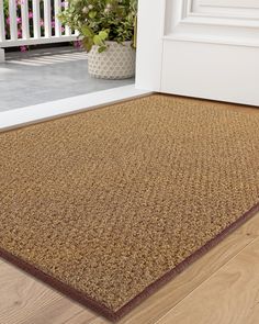 a close up of a door mat on the ground near a porch with potted plants