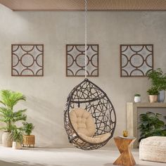 a hanging chair in the middle of a room with potted plants on the wall