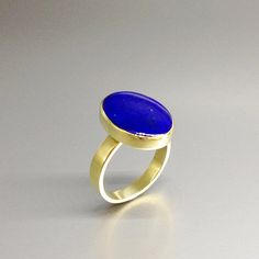 Oval classic Lapis Lazuli ring with 18k gold. Unique gift for her, girlfriend, wife, September and December birthstone, anniversary gift. This ring is a timeless classic and lets the stone speak with all its natural beauty. This beautiful ring is worked with the technique of inlay, which means the stone is worked seamlessly into the 18K gold.All our stones are natural stones and our jewelry is handmade, slight differences in color and size may occur. Our inlay work is made with real stone and NO Blue 14k Gold Oval Cabochon Rings, 14k Gold Blue Oval Cabochon Rings, Elegant Gold Rings With Tanzanite, Gold Sapphire Ring With Smooth Bezel, Elegant Gold Tanzanite Rings, Timeless Sapphire Ring Gift, Elegant Blue Jewelry With Smooth Bezel, Fine Jewelry Sapphire Ring With Smooth Bezel For Anniversary, Elegant Birthstone Ring With Smooth Bezel For Wedding