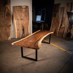 a table made out of wood and metal in a room with other wooden pieces on the floor