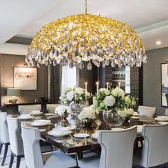 a dining room table with white chairs and a chandelier hanging from the ceiling