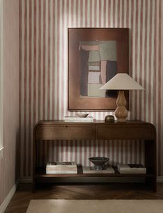 a room with striped wallpaper and a painting on the wall next to a table