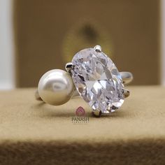 a diamond and pearl ring sitting on top of a piece of cloth next to a box