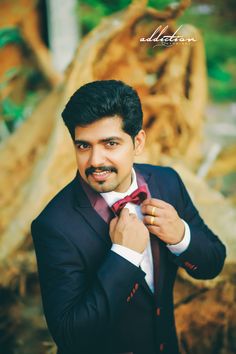 a man in a tuxedo is adjusting his bow tie and posing for the camera