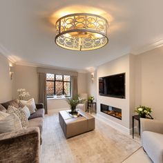 a living room filled with furniture and a flat screen tv mounted on the wall next to a fire place