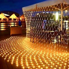 an outdoor area with lights on the floor and a white tent in the background at night