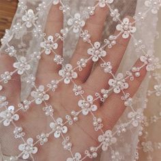 a close up of a person's hand wearing a veil with flowers on it