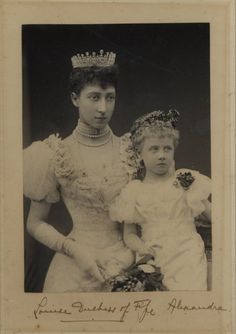 an old black and white photo of two women in dresses with tiaras on their heads