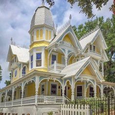 a yellow and white victorian style house on a cloudy day