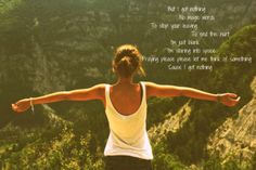 a woman standing on top of a mountain with her arms spread out to the side