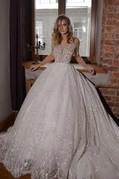 a woman in a wedding dress standing by a window