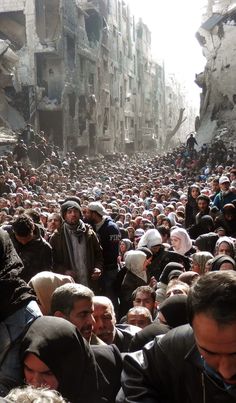 a large group of people standing in the middle of an alleyway filled with buildings