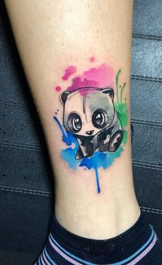 a small panda bear tattoo on the right side of the leg with watercolor splashs