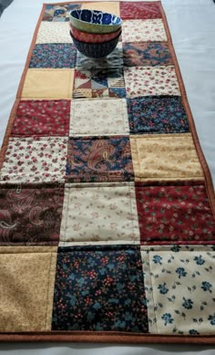 a bowl is sitting on top of a quilted table runner