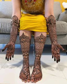 a woman sitting on top of a couch covered in hendikes and legs decorated with intricate designs