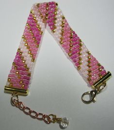 pink and white beaded bracelet with gold tone metal clasps on chain or keychain