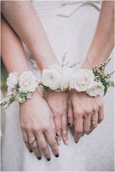 two brides holding hands with white flowers on them