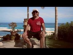 a man sitting on top of a chair next to the ocean in front of palm trees