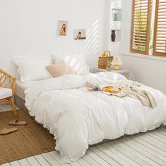 a bed with white linens and pillows in a bedroom next to a wicker chair