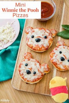 mini winnie the pooh pizzas on a wooden tray with stuffed animal toy next to them