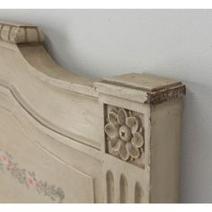 an old white bed with flowers on the headboard and foot board, against a white wall