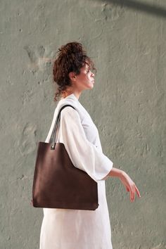 "This is a minimalist tote leather handbag, yet very elegant and classy, with high quality finishing outside and inside. Perfect for all shopping purposes, or as a laptop bag. ** SIZE:  15\"x15\"(38cmx38cm)  ** COLOR:  Available in Brown. Other colors Upon Request. ** SHIPPING POLICY:  All deliveries within 7-10 business days. In case of any delay due to the current pandemic, we will notify you ahead of time. 25 dollar flat-rate \"Door to Door\" delivery worldwide where  delivery is available. I Modern Square Bags With Smooth Grain, Minimalist Brown Bag With Leather Handles, Minimalist Brown Bags With Leather Handles, Minimalist Smooth Grain Shoulder Bag For Shopping, Minimalist Double Handle Shoulder Bag With Leather Lining, Minimalist Brown Bag With Smooth Grain, Minimalist Bags With Leather Handles, Minimalist Square Leather Bag, Square Textured Leather Everyday Bag