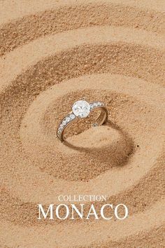 a diamond ring sitting on top of sand with the words collection monaco written below it