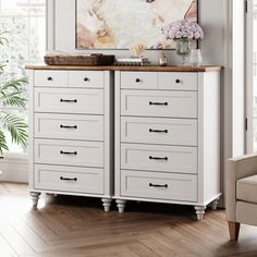 a white dresser with drawers and pictures on the wall