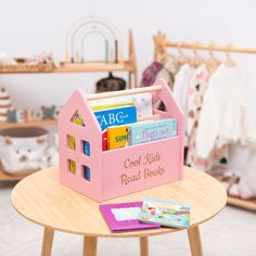 a wooden table with a pink toy house on top of it and books in the middle