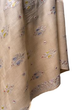 Celebrate the subtle elegance of our "Beige Blossom Tilla Enchantment Pashmina," a shawl that resonates with the gentle beauty of a blossoming garden under the soft Kashmir sun. Adorned with hand-embroidered sozni work, it features delicate motifs inspired by the region's flora, brought to life with a kiss of color and the sparkle of tilla embroidery. Drape yourself in this embodiment of quiet sophistication, a pashmina that complements every occasion with its understated glamour and refined all Luxury Chikankari Embroidered Shawl, Luxury Beige Pashmina Shawl With Embroidered Border, Embroidered Pashmina Shawl For Transitional Seasons, Elegant Beige Traditional Wear With Floral Embroidery, Beige Bohemian Traditional Wear For Wedding, Bohemian Traditional Wear For Wedding In Beige, Beige Jamawar Dupatta With Intricate Embroidery, Elegant Multicolor Embroidered Fabric For Diwali, Transitional Raw Silk Fabric With Floral Embroidery