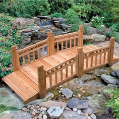 a wooden bench sitting on top of a rock covered ground next to a creek and trees