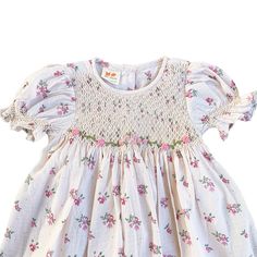 This lovely dress features a cream-colored fabric adorned with delicate pink and purple flowers. The smocked detailing adds a charming touch to the overall design, making it a perfect choice for a stylish and elegant look.  * 100% Cotton * 2 layers * Handmade * Tie at the back * Lightweight, soft cotton, comfortable * Hand wash or machine wash on a delicate setting We are based in Sydney, New South Wales, Australia. Within Australia, Standard shipping is $7 flat rate via AusPost. There is option Spring Floral Print Smocked Dress With Short Sleeves, Spring Smocked Dress With Short Sleeves And Floral Print, Short Sleeve Smocked Dress With Floral Print For Spring, Short Sleeve Smocked Dress With Floral Print, Sweet Floral Print Spring Dress, Sweet Beige Summer Dress, Spring Feminine Smocked Dress With Ditsy Floral Print, Feminine Smocked Dress With Ditsy Floral Print For Spring, Floral Dress With Smocked Bodice For Garden Party