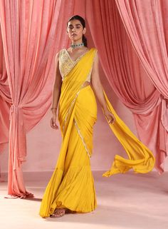 Elevate your style with this exquisite pairing: an embellished choli perfectly complemented by a pre-stitched tiered sari, featuring intricate embellishments on the pallu. This ensemble exudes elegance and charm, making it the perfect choice for any special occasion. Fitted Yellow Pre-draped Saree With Pallu, Festive Yellow Fitted Pre-draped Saree, Elegant Yellow Saree With Mirror Work, Elegant Yellow Pre-draped Saree With Traditional Drape, Elegant Yellow Fitted Pre-draped Saree, Yellow Chinon Pre-draped Saree, Yellow Pre-draped Saree With Mirror Work For Wedding, Fitted Yellow Pre-draped Saree With Mirror Work, Fitted Yellow Pre-draped Saree For Festivals