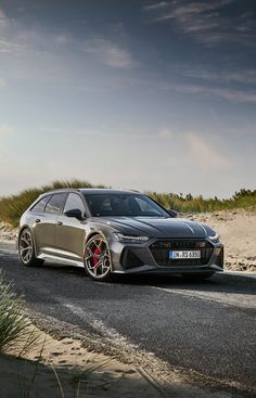 a grey car parked on the side of a road next to grass and sand dunes