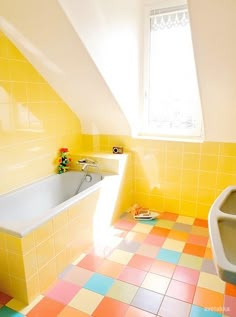 a bathroom with yellow and pink tiles on the floor, tub and toilet in the corner