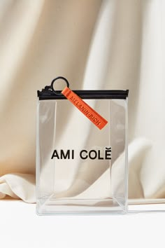 a clear bag with an orange tag hanging from it's side on a white surface