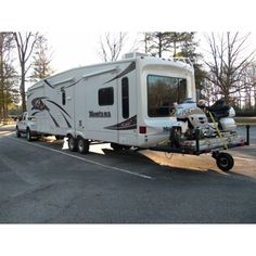 a motor home being towed down the street by a motorcycle on a trailer attached to it