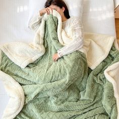 a woman laying in bed covered with a blanket and covering herself from the cold weather