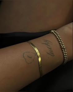 a woman's arm with a gold bracelet and name written on it, in cursive writing