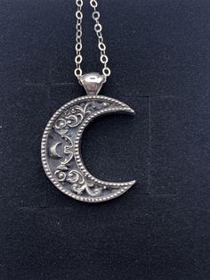 "A crescent shaped moon with a solid bail. Inside the moon is a floral scrollwork pattern. We cast this is solid sterling silver, with a dark patina to really make it pop! Pendant including bail is 26mm high and 20mm wide. This item is custom made to order. That means it may take an extra second or two to make your entire piece by hand. We try to beat shipping estimates, but its just a one woman team in this shop! Our supplier of casting grain uses SCS-certified 100% recycled metal. We make ever Moon Pendant Necklace Silver, Vintage Moon Shaped Sterling Silver Jewelry, Vintage Sterling Silver Moon Jewelry, Vintage Moon-shaped Sterling Silver Jewelry, Engraved Sterling Silver Crescent Jewelry, Silver Oxidized Moon Shaped Jewelry, Antique Silver Crescent Jewelry, Silver Half Moon Jewelry Engraved, Silver Half Moon Engraved Jewelry