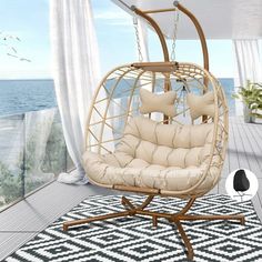 a swing chair with pillows on top of it in front of a window overlooking the ocean