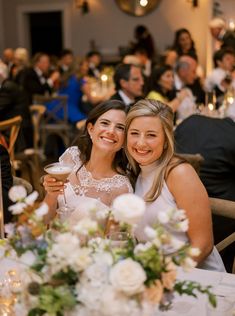 two women sitting at a table with wine glasses