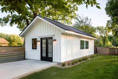 a small white shed sitting on top of a lush green field