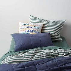 a bed with blue and green pillows on top of it