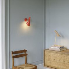 a wooden chair sitting next to a table with a lamp on the wall above it