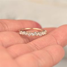 a woman's hand holding a gold wedding band with five diamonds on the side