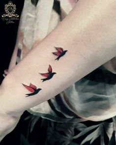 a woman's arm with three birds on it and one bird flying in the air