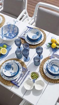 the table is set with blue and white plates, silverware, and lemons