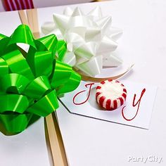 two different types of bows on top of a white table next to a card with the word joy